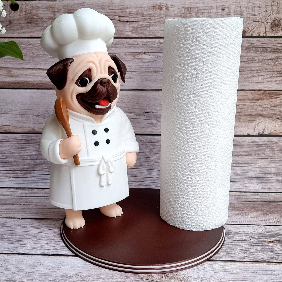 Pug chef paper towel holder with a full roll loaded, standing on its round wooden-look base