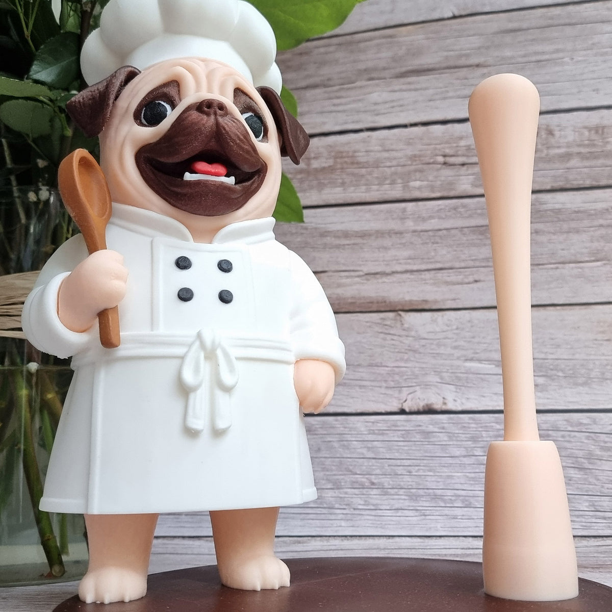The pug chef beside greenery, bare rod, showing the full height of the figure