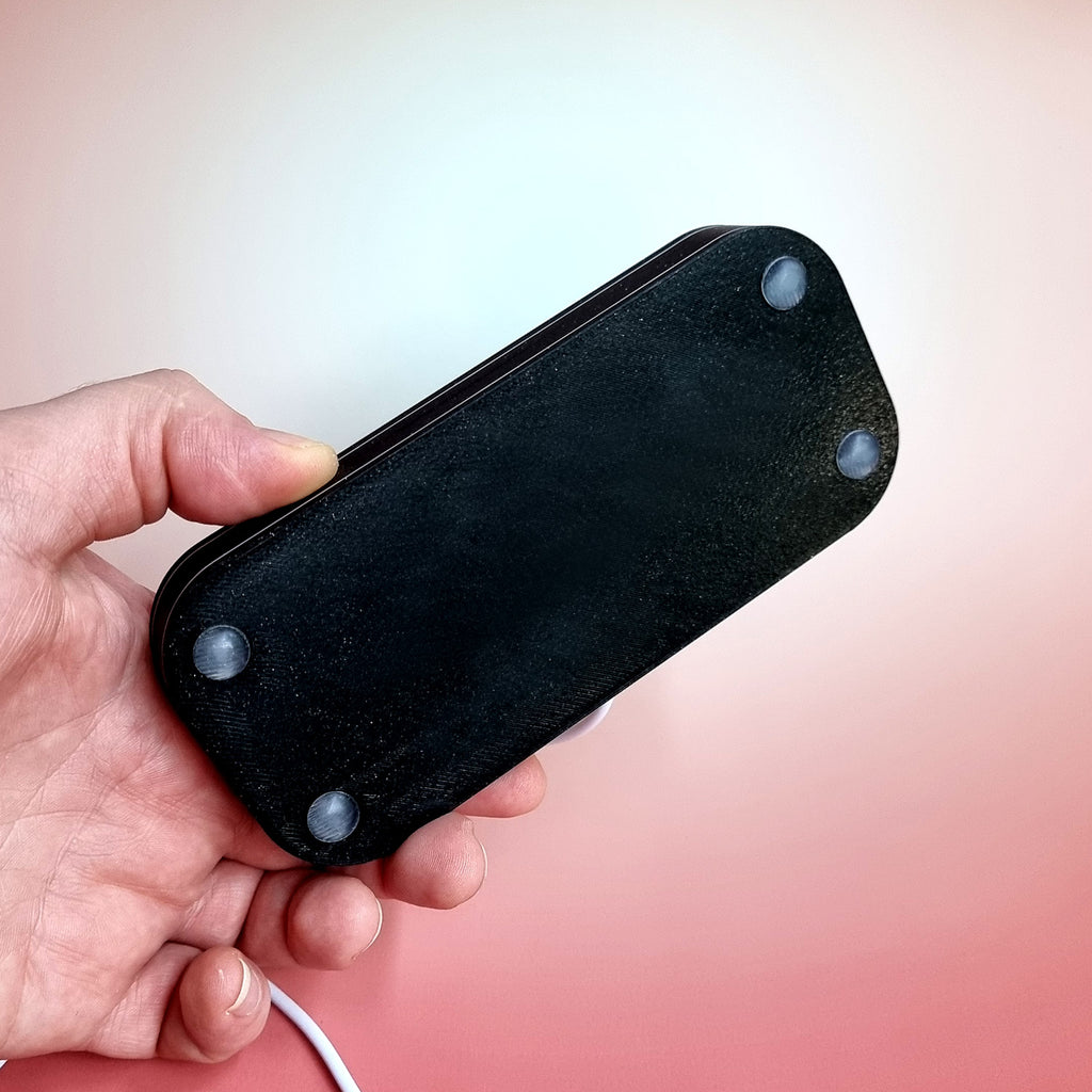 The underside of the display base held in one hand, showing its four rubber feet