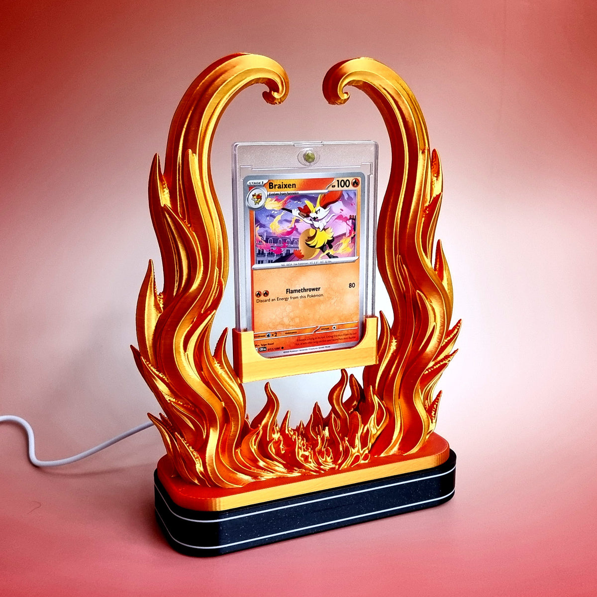 The gold and red flame holder standing on the black illuminated base, light off, USB cable running off to the side